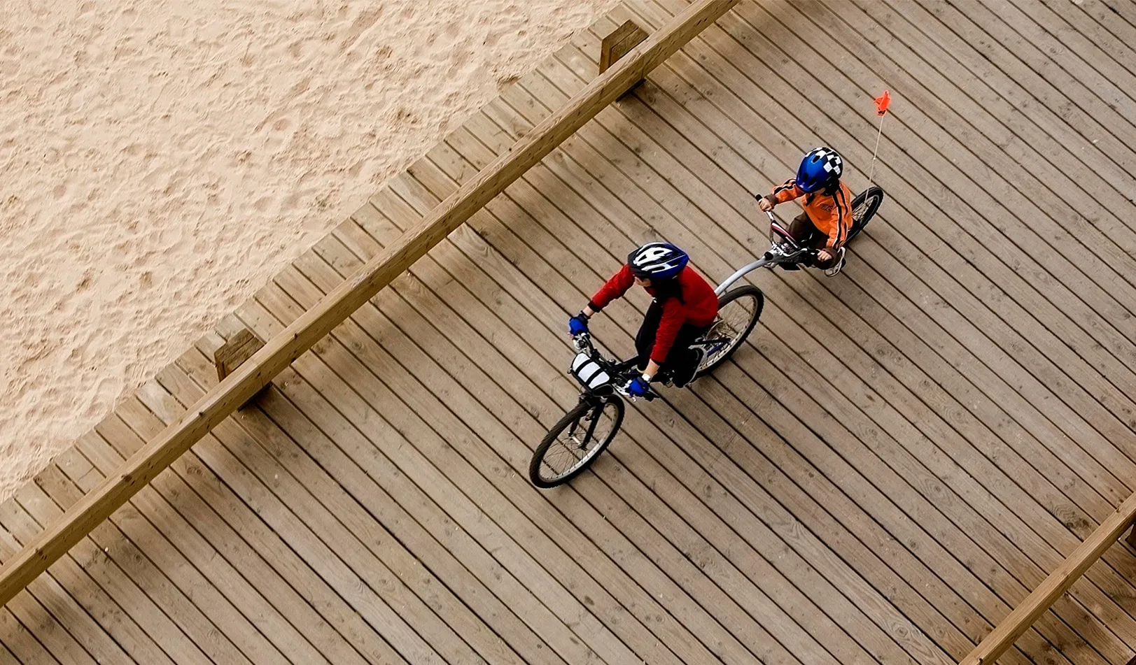 A parent and child ride a bicycle built for two along the beach