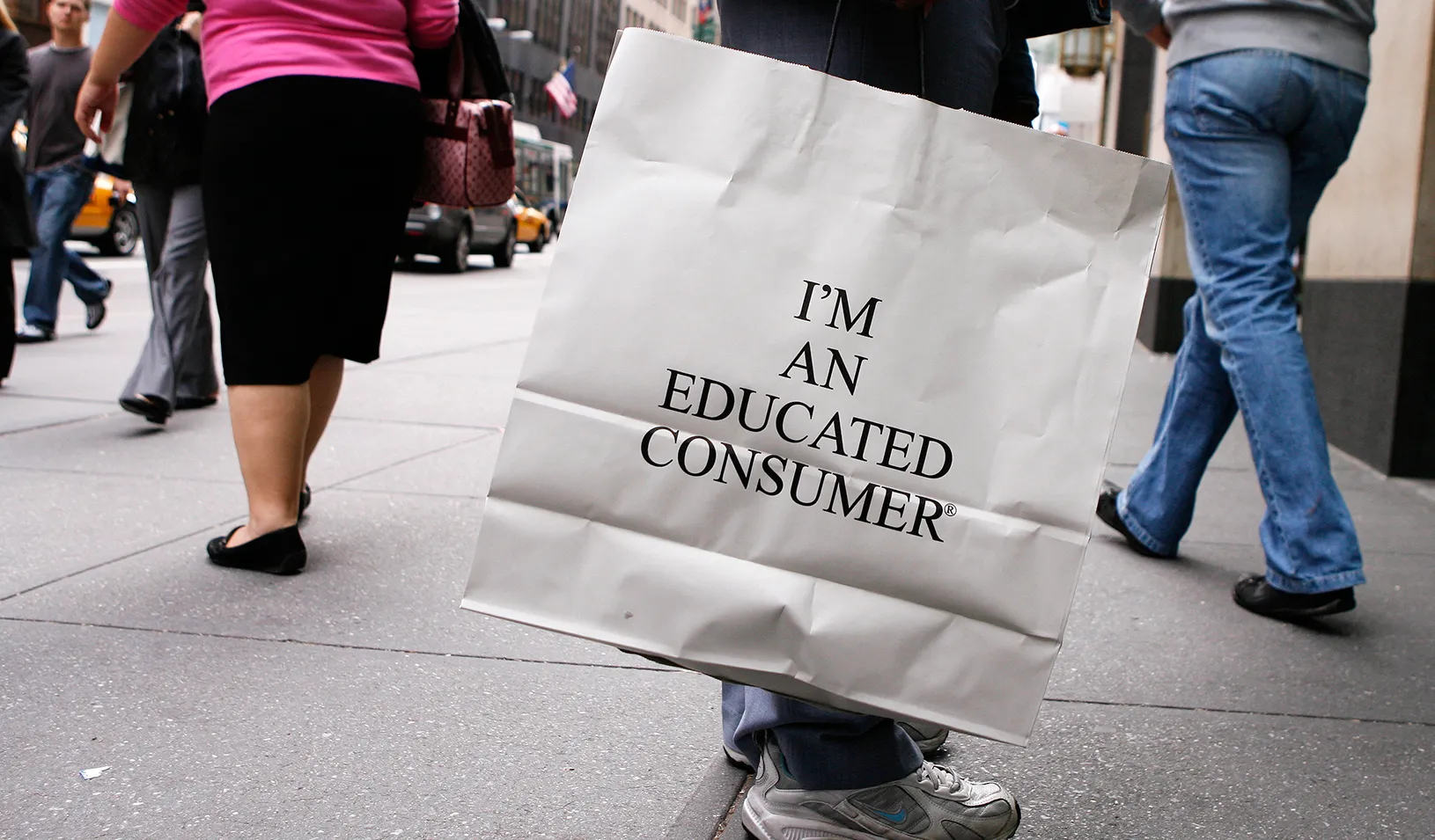 A person holding a shopping bag that says "I'm an educated consumer"