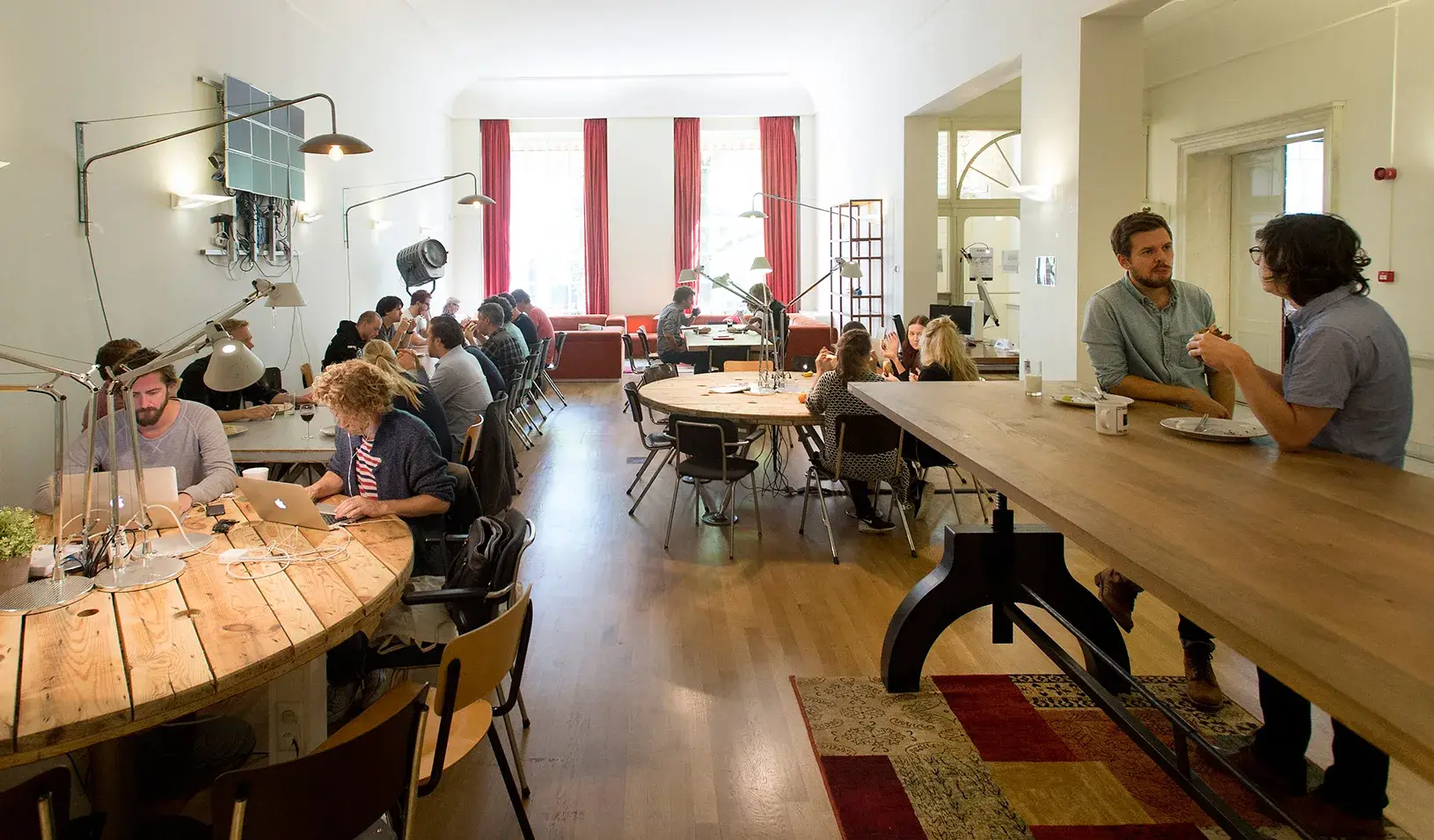 People working at various tables in an office space