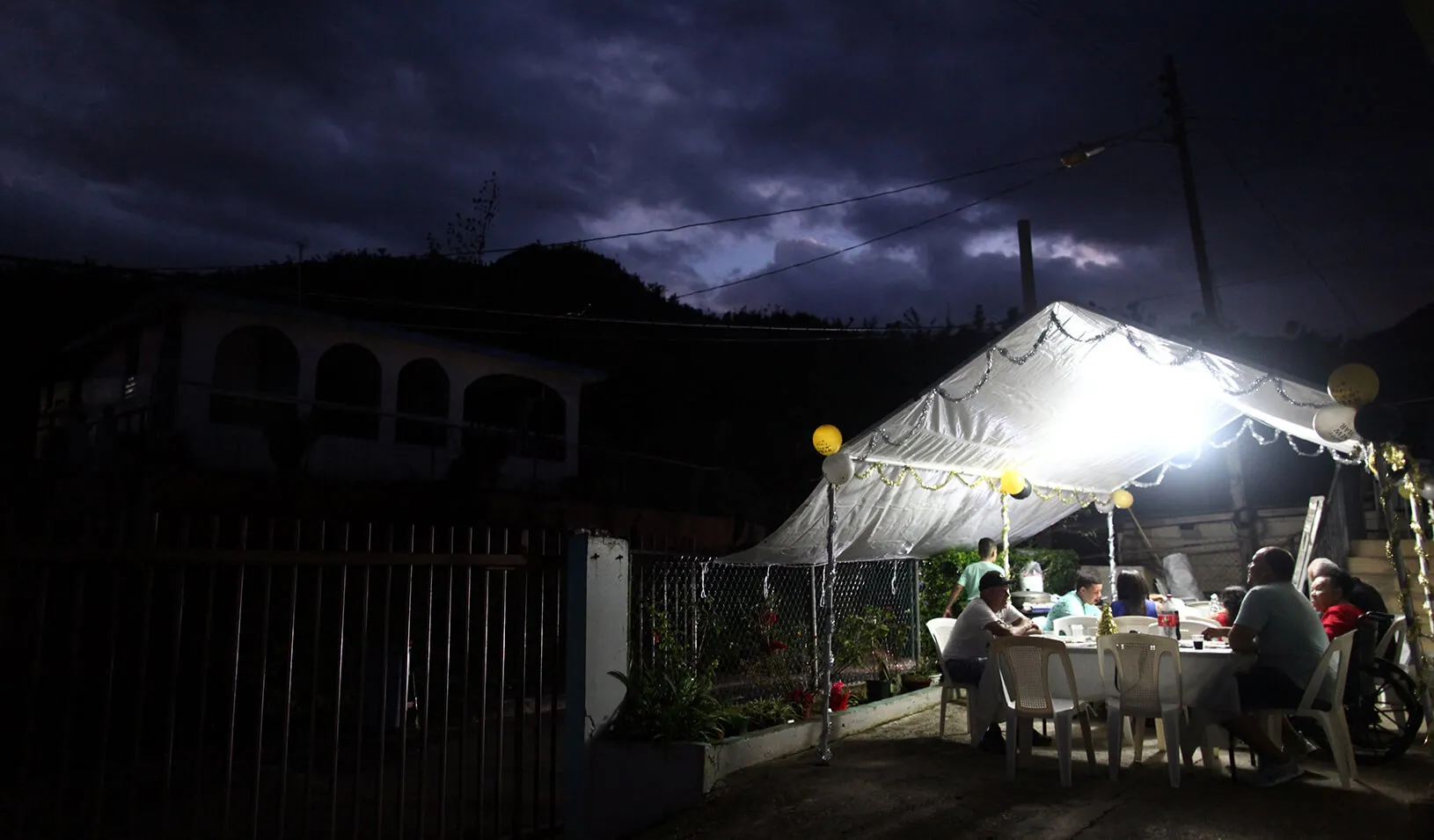 Residents of the El Salto neighbourhood share a meal during New Year's Eve after Hurricane Maria damaged the electrical grid in September, in Morovis, Puerto Rico December 31, 2017. | REUTERS/Alvin Baez