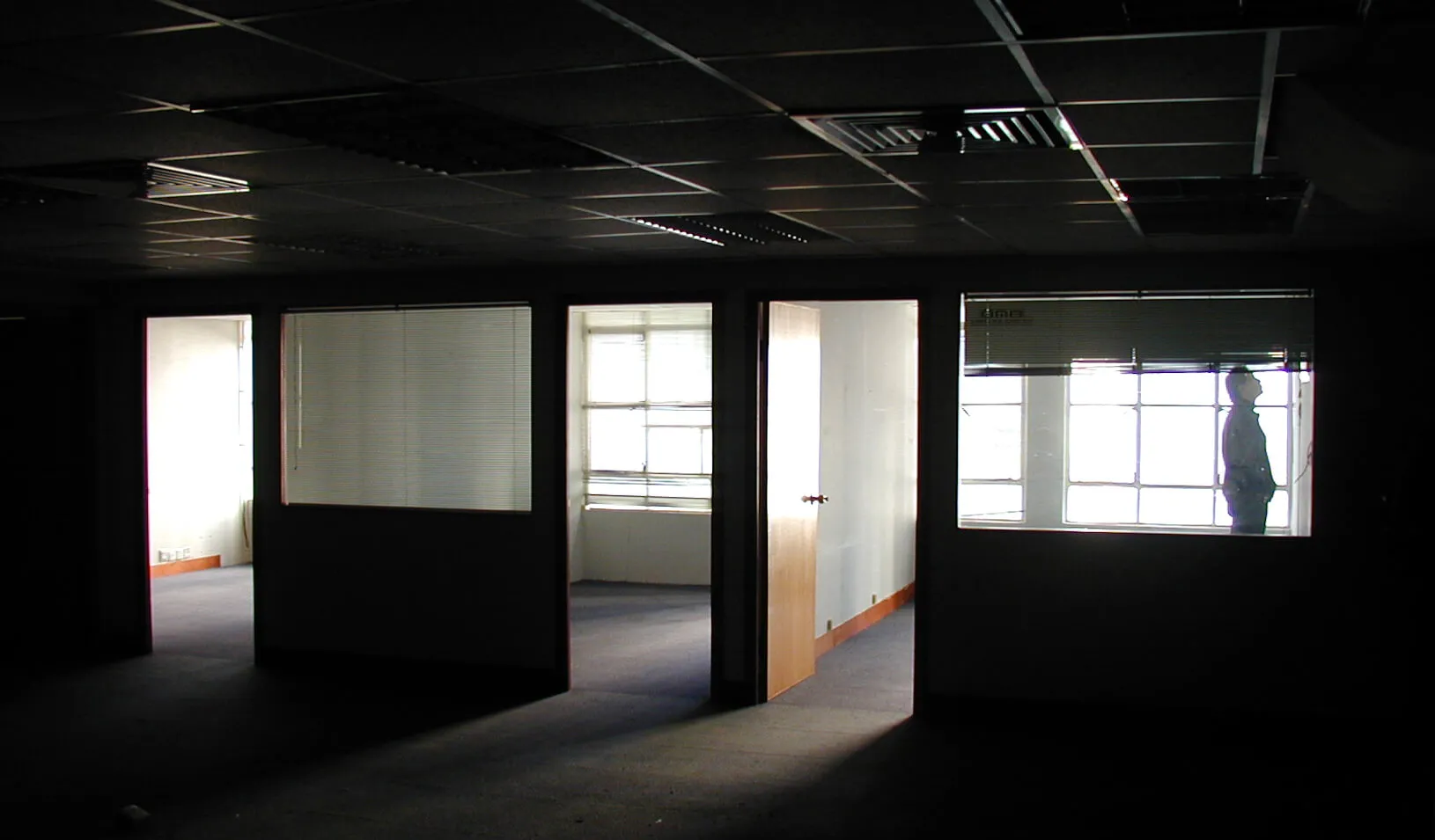 Man stands alone in dark abandoned office building. Credit: istock/blackred