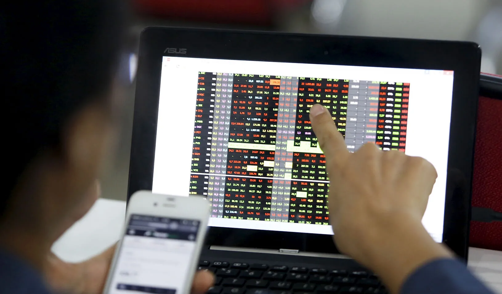 user pointing at computer screen showing stock prices
