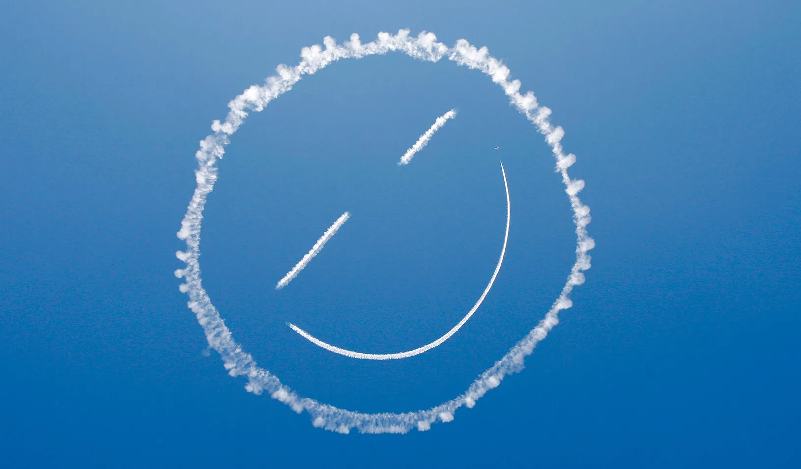A plane "sky writes" a smiley face in the sky.