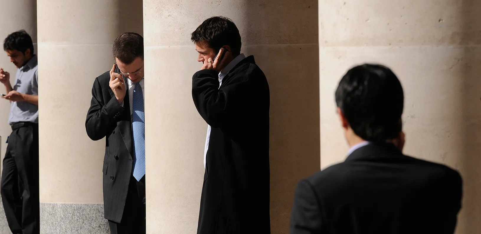 City workers make phone calls outside the London Stock Exchange