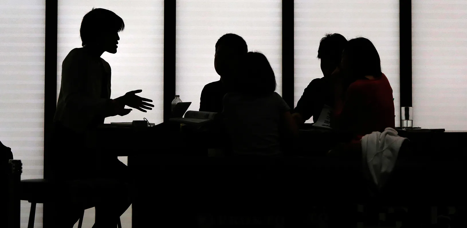 Silhouetted people holding a meeting