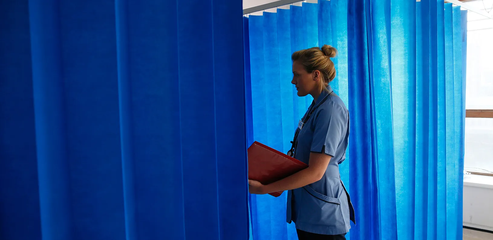 Health care worker talking to a patient behind a privacy curtain