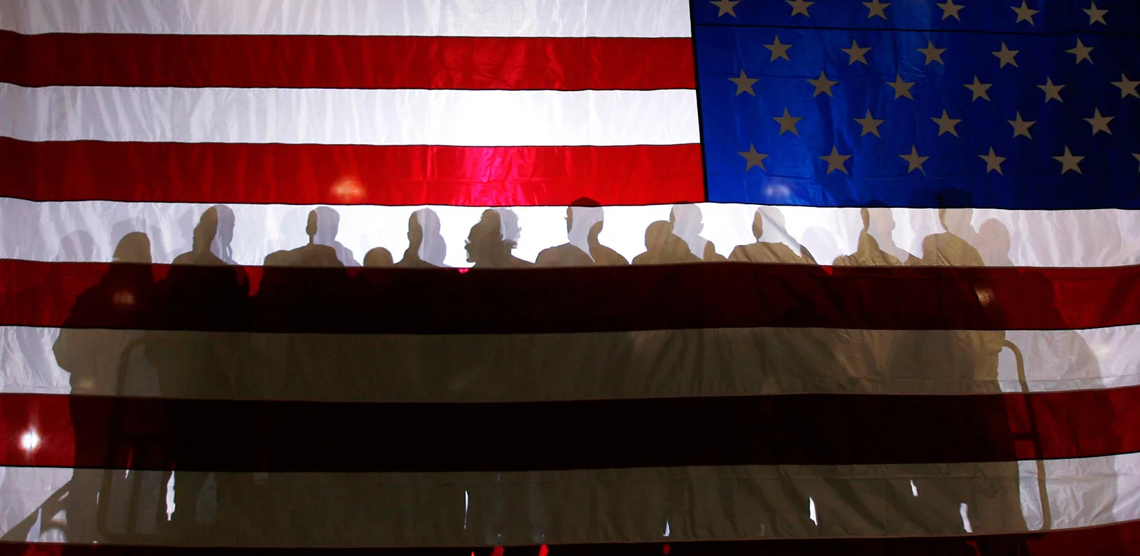 Shadows of a group of people against an American flag backdrop