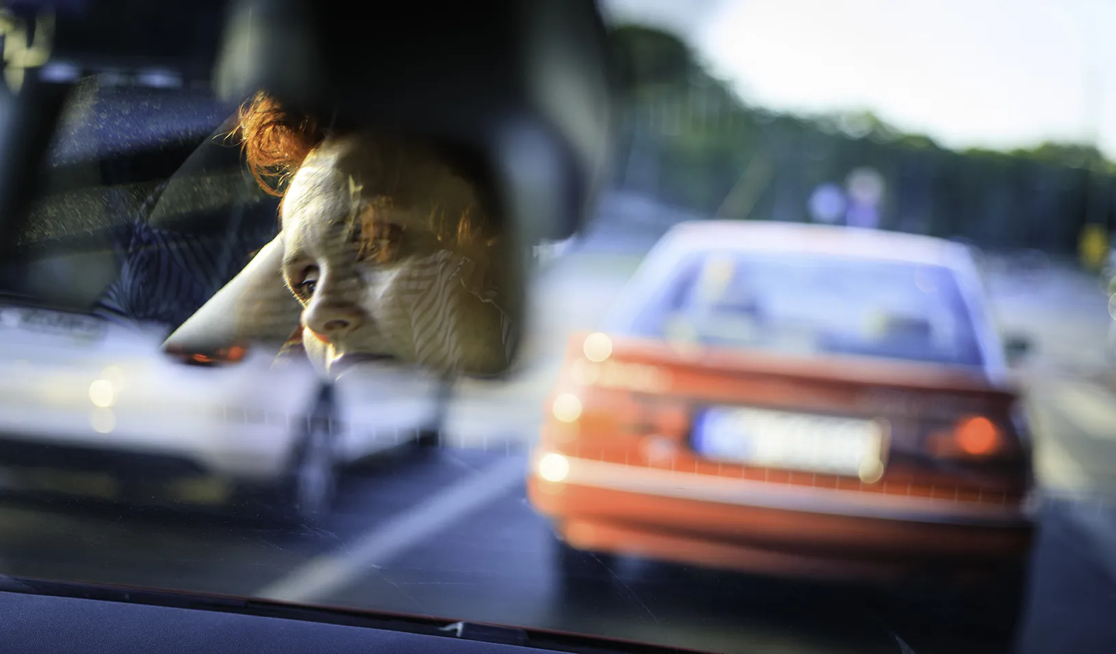 Woman driving in traffic, looking stressed through her rearview mirror. Credit: iStock/Republica