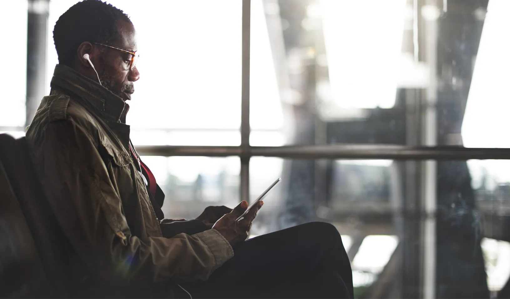 An African American businessman watching videos on his tablet at the airport. Credit: iStock/rawpixel