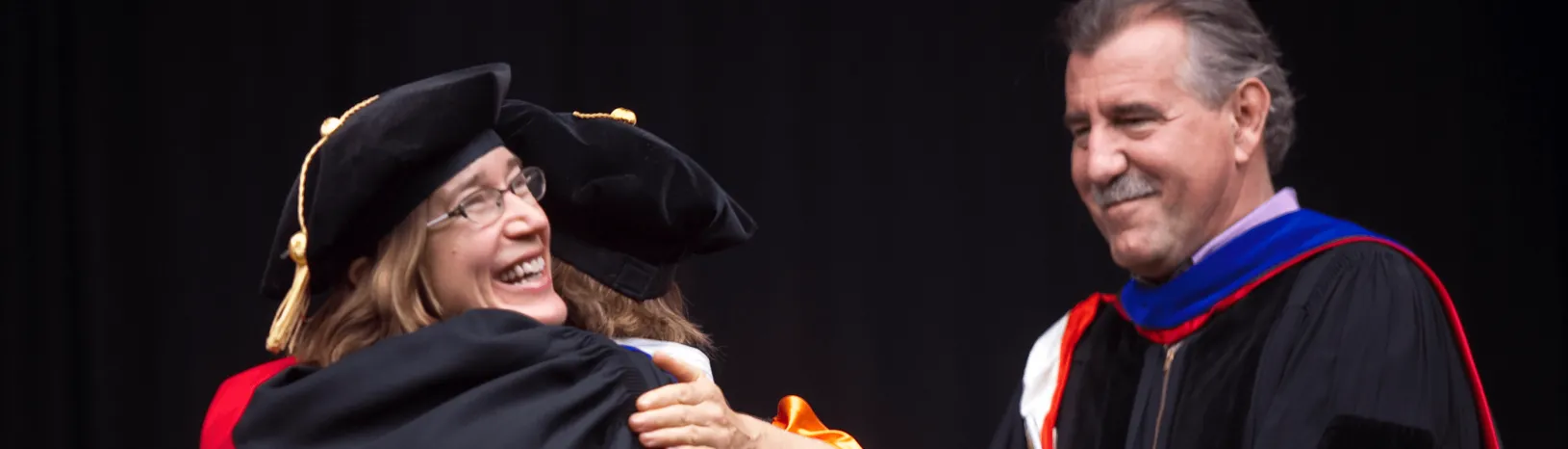 Erica Plambeck, Professor of Operations, Information, and Technology, hugging a student during a commencement ceremony. Credit: Saul Bromberger