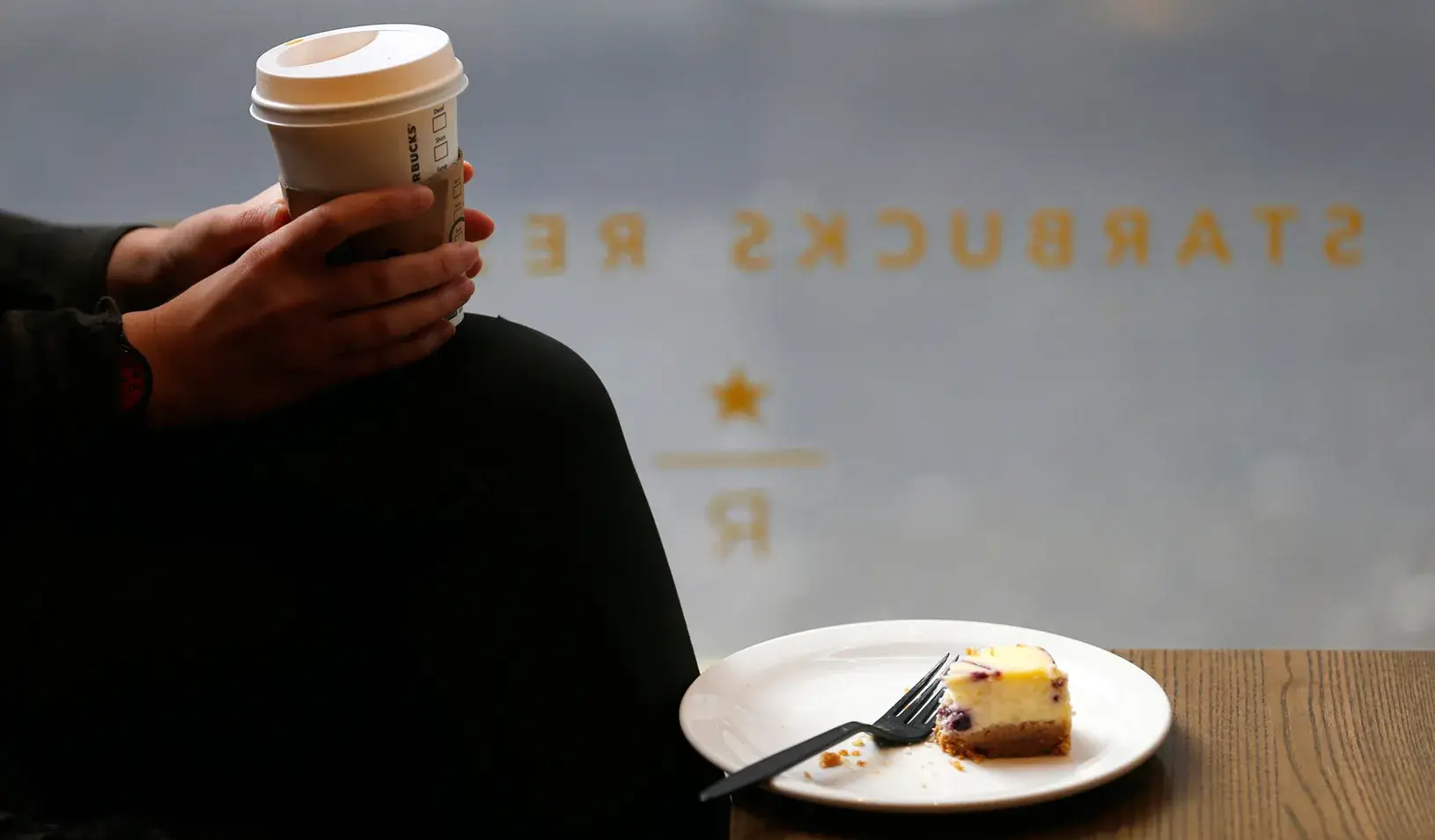 A customer cradles her drink at a Starbucks in central London. (Reuters photo by Andrew Winning)