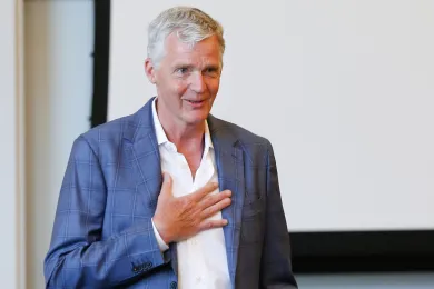 David Dodson in a classroom, smiling with his hand on his chest.