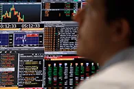 Man watching several monitors with financial charts and graphs on them