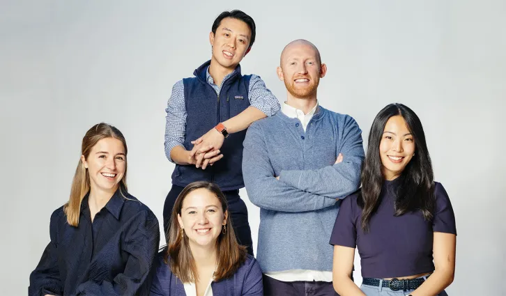 Students from the GSB Energy Club, posing and smiling together in front of a light blue background. From top to bottom, left to right: David Liou, Caleb Cunningham, Louise Hannecart, Amy Zhao, Louise White. Photo by Elena Zhukova