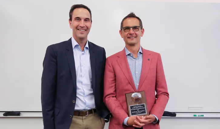  Jon Levin stands next to Andrzej Skrzypacz as he holds his MBA Distinguished Teaching Award. Photo by Sher Bhullar