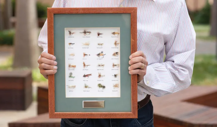 Charles M. C. Lee holds the shadow box of fly-fishing flies given to him by students in one of his investment classes. | Toni Bird