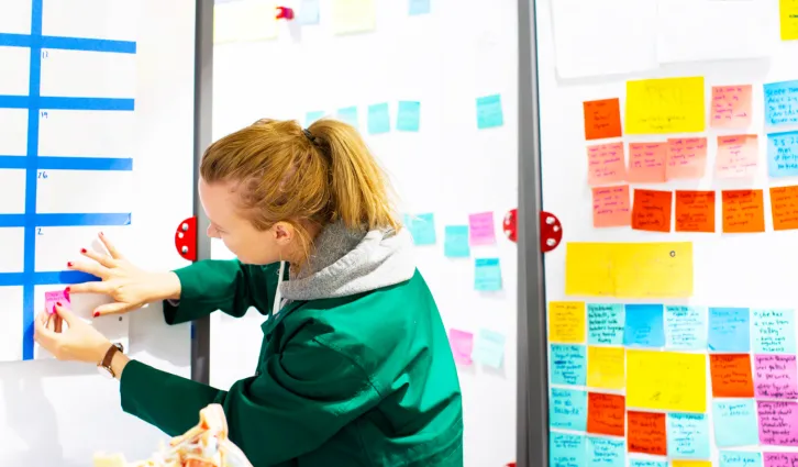 A woman using post-its to brainstorm at the d.school. Credit: Elena Zhukova