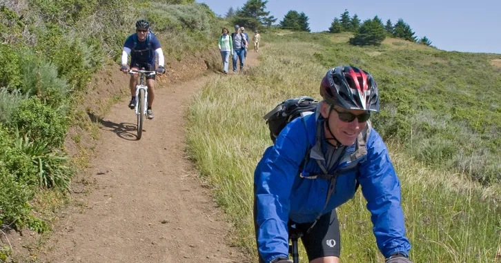 A mountain biker smiles as she rides down a hill.