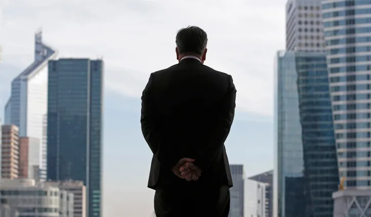 A man broodily looking over a city skyline from a high window | Reuters/Christian Hartmann 