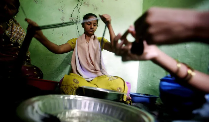 A customer of a micro finance institution strings beads into necklaces at a workshop in a slum area in Mumbai. Credit: Reuters/Prashanth Vishwanathan