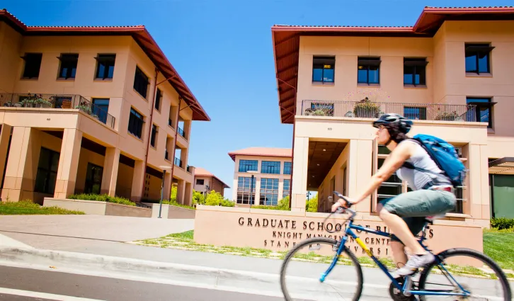A woman rides her bike past the Knight Management Center. Credit: Elena Zhukova