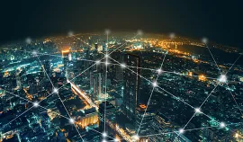 Nighttime birds eye view of a city with interwoven web of lines that connect the city in an energy grid. iStock/Chaay Tee