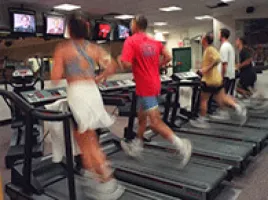 Three people running on treadmills at a gym