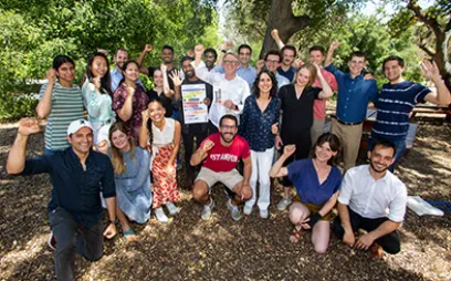 John Doerr and Ryan Panchadsaram outside on Stanford GSB campus, posing for a group photo with Stanford GSB students. Photo by Saul Bromberger