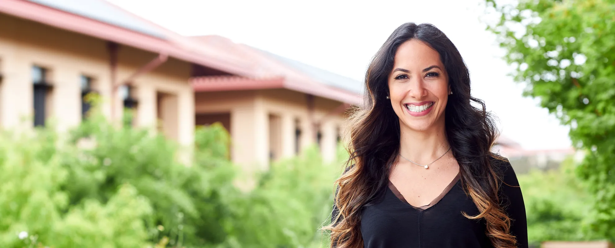 Stanford GSB Sloan Alumnus Lamiaa Daif standing outside on a sunny day smiling at the camera. | Nancy Rothstein and Rachel Garrison.