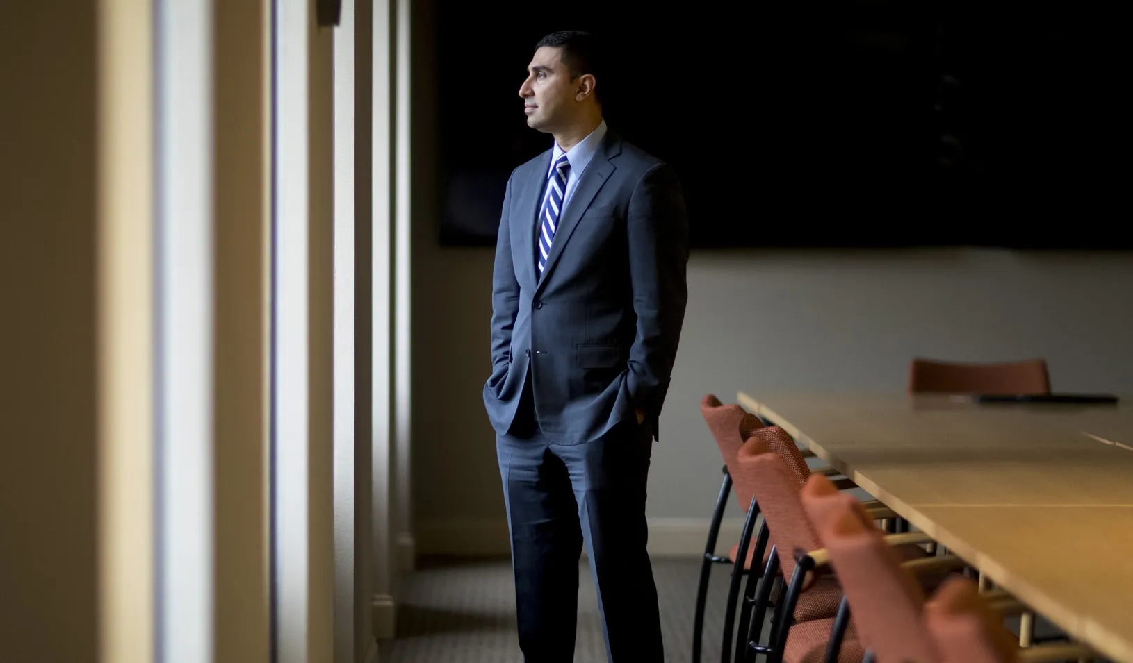 portrait of Faiz Shakir standing in an empty conference room