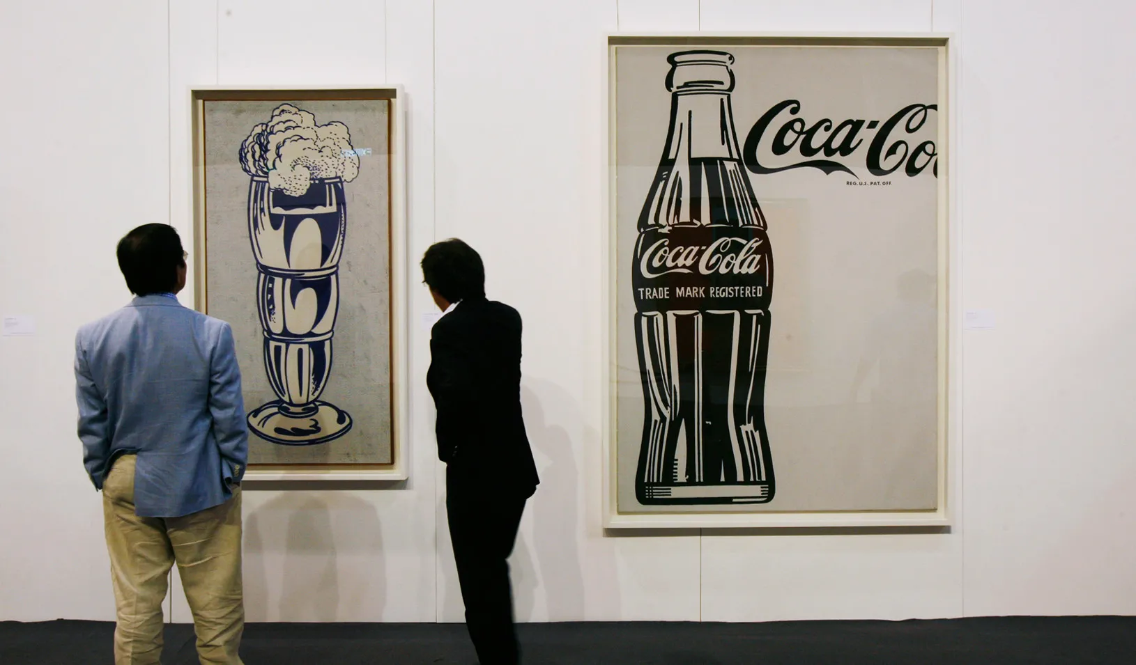 People view the artworks "Coca-Cola" (R) by Andy Warhol, and "Ice Cream Soda," by Roy Lichtenstein, on display at the Sotheby's Autumn Sales in Hong Kong.