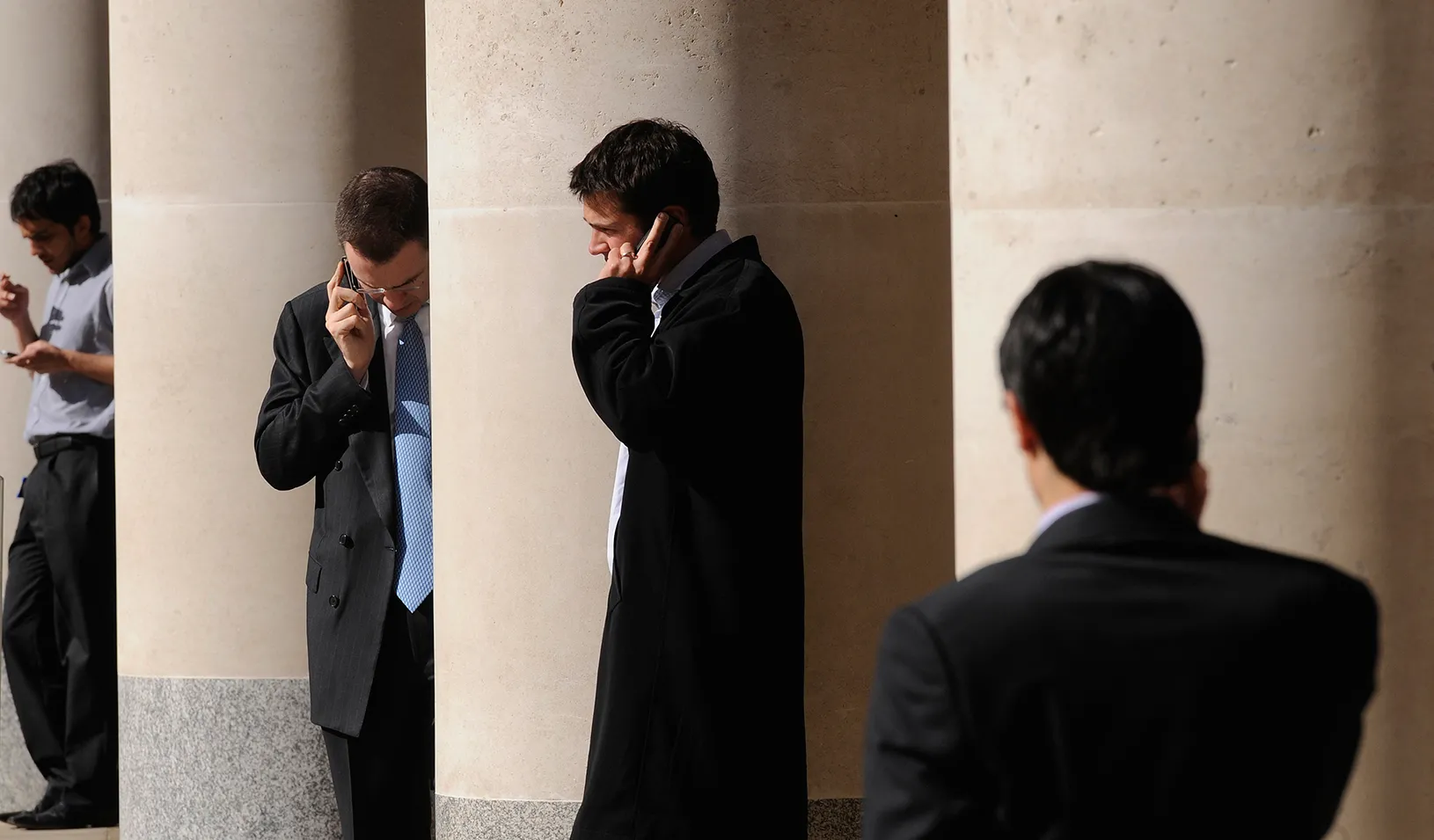 City workers make phone calls outside the London Stock Exchange