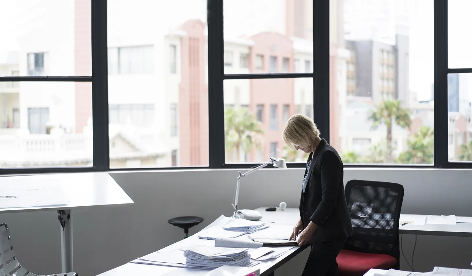 An older woman standing at her desk. Credit: iStock/Portra