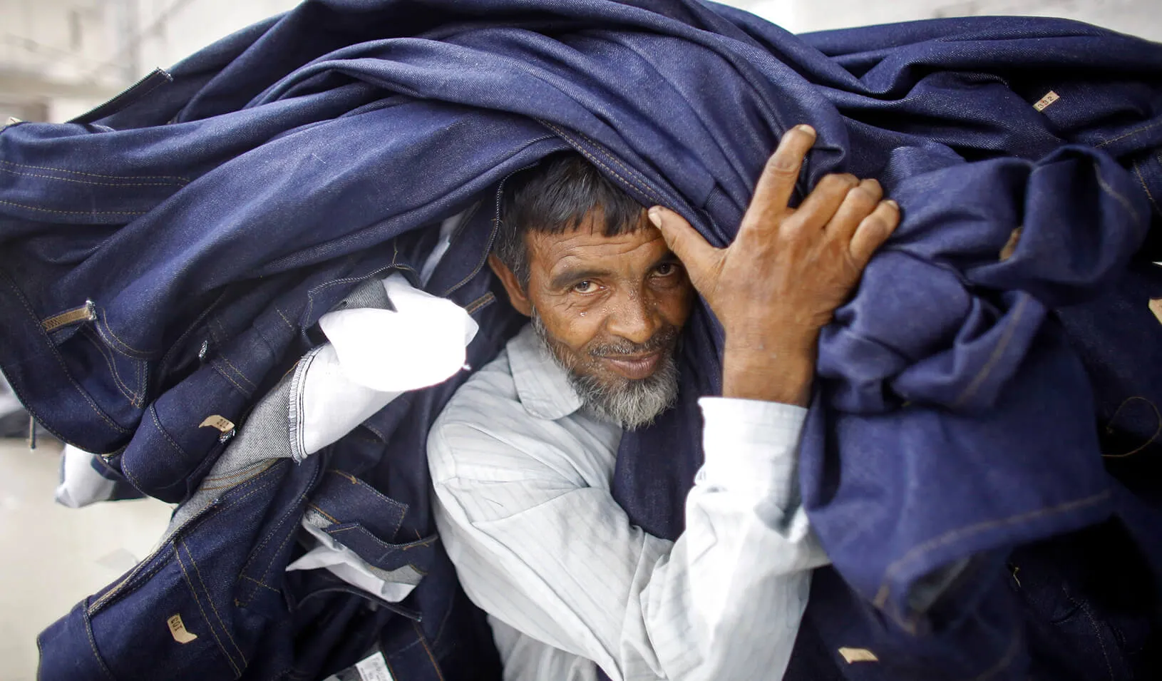 A worker carries a stack of clothes in a garment factory | Reuters/Andrew Biraj