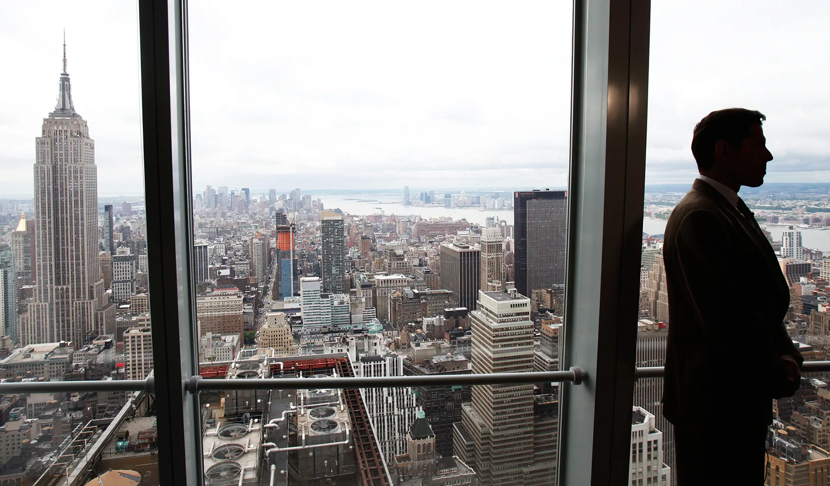 Man standing in front of office window overlooking Manhattan