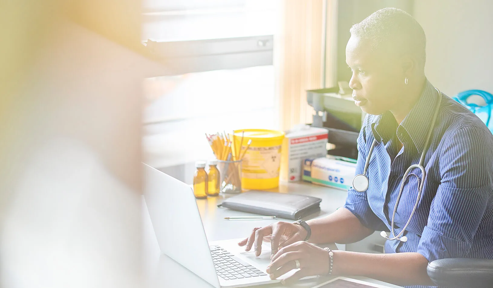 A doctor in her office, working on her computer | iStock/sturti