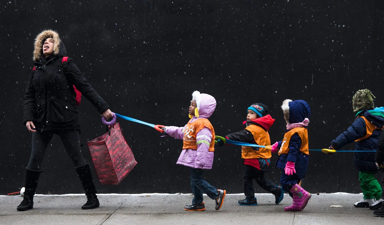 A schoolteacher attempts to catch snowflakes while leading her students to a library from school  | Reuters/Adrees Latif 