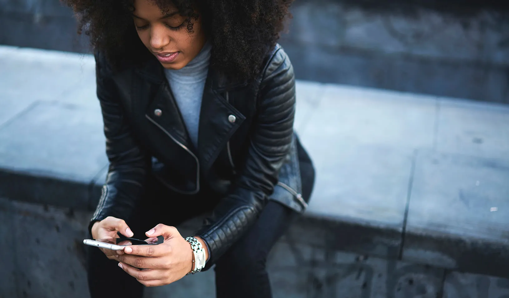 a woman looks at her mobile phone | iStock/GaudiLab