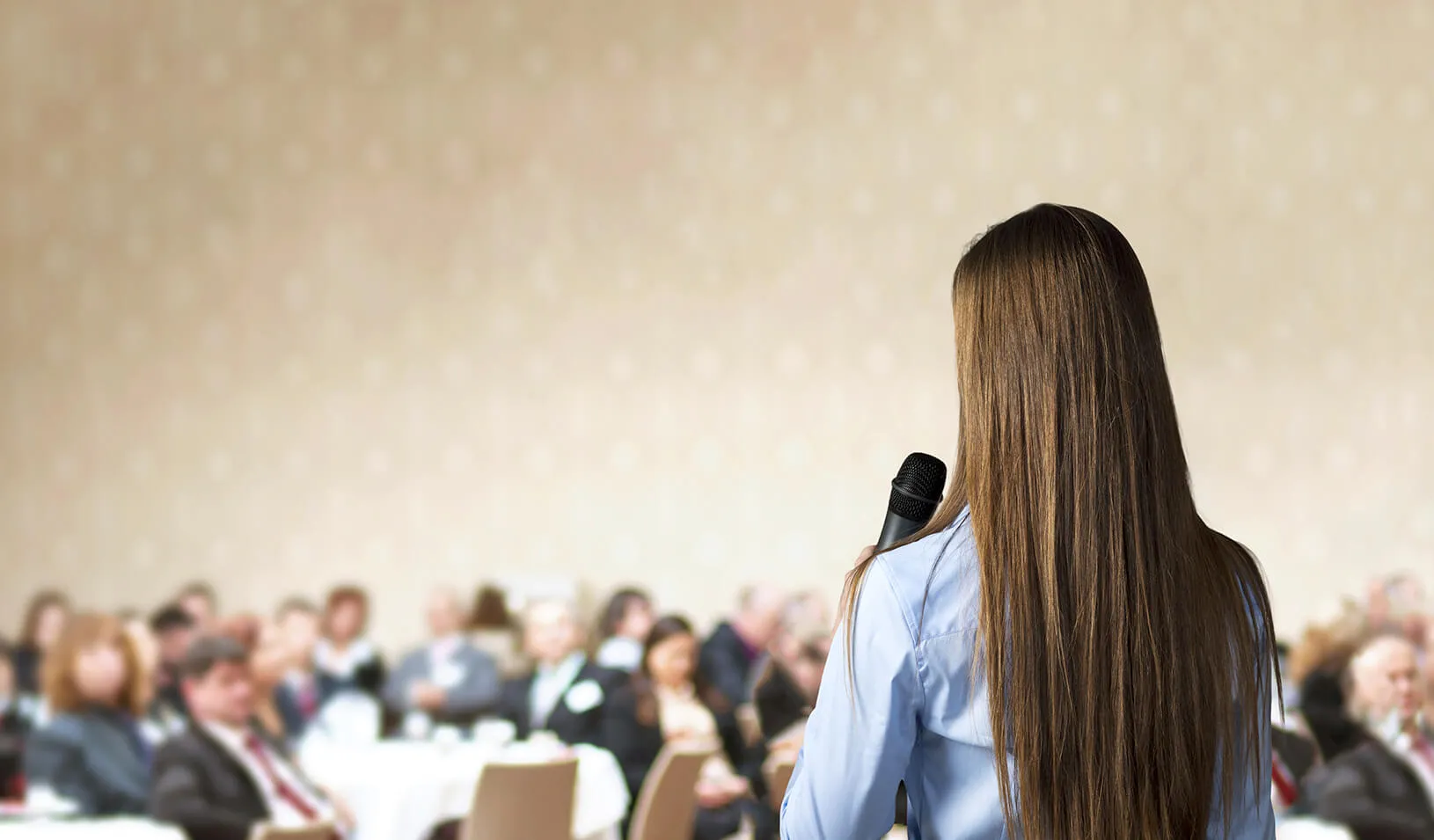 Woman speaking in front of a crowd|  iStock/Halfpoint