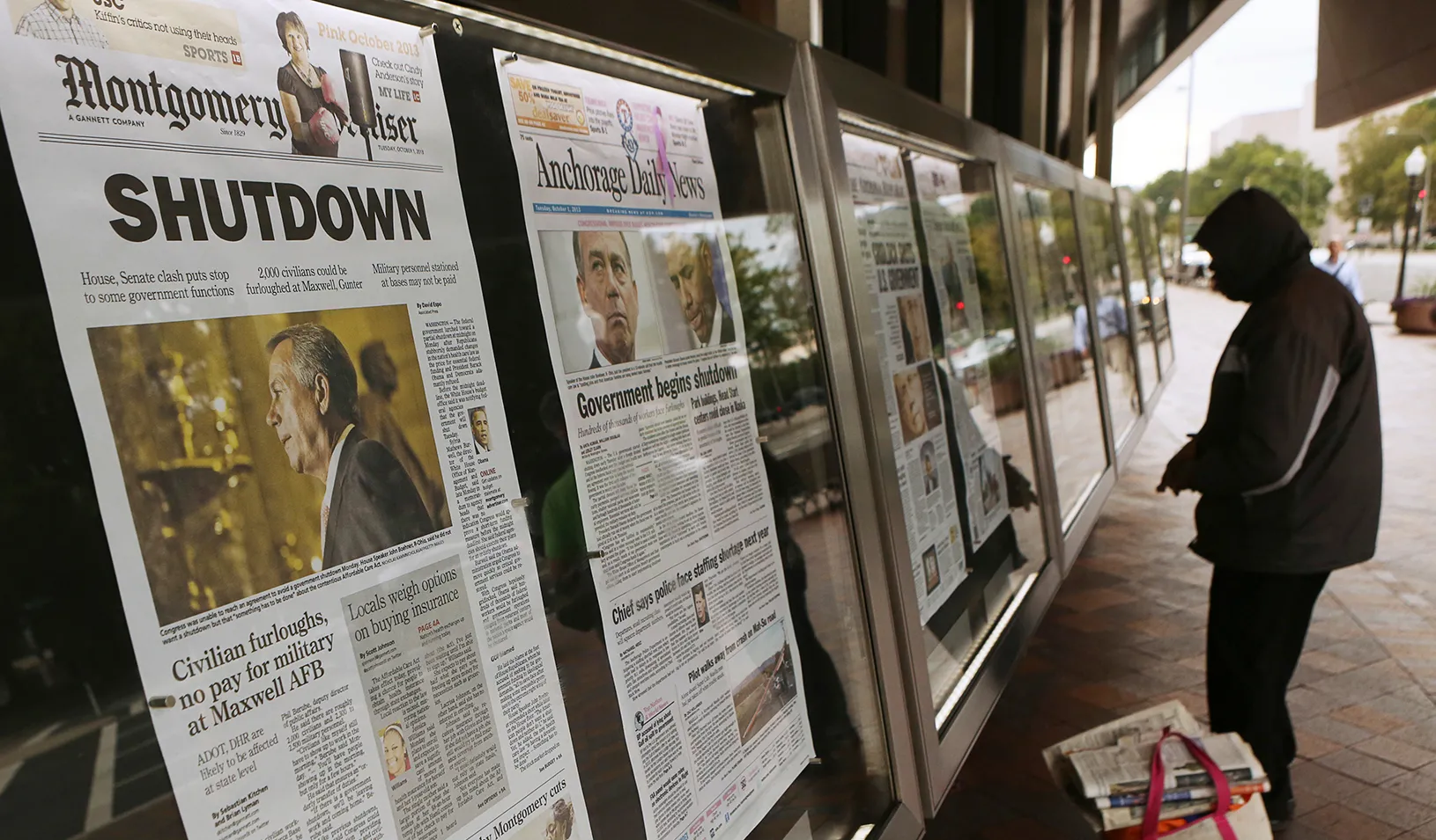 A man looking at newspaper headlines hanging on a window. | Reuters/Gary Cameron