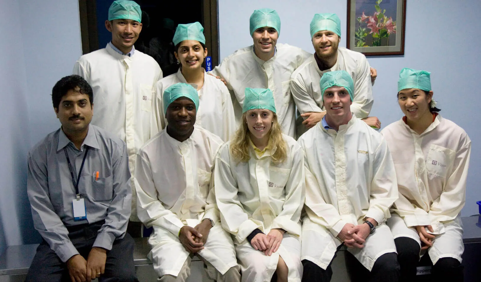 Zachary Levine (top row, far right), and other students visit Aurolab, where Aravind Eye Hospital makes low-cost lenses for cataract surgeries, among other low cost medical and surgical products. | Peter Deutsch