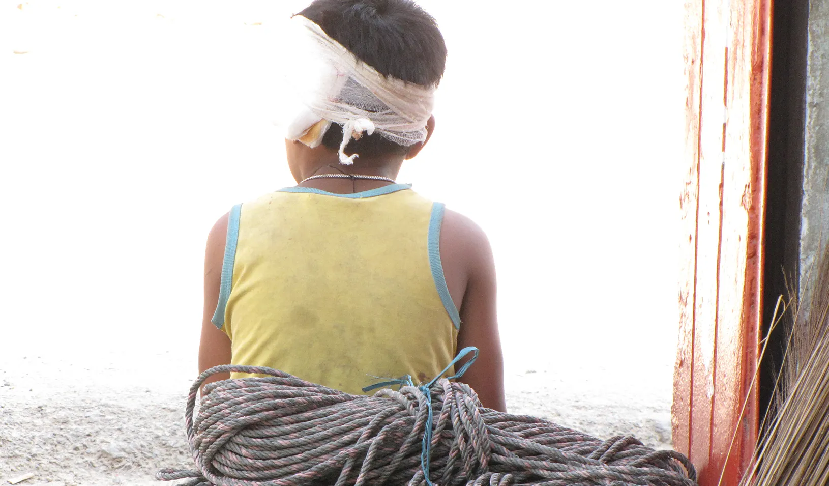 a boy with a bandaged around his head looking out a window