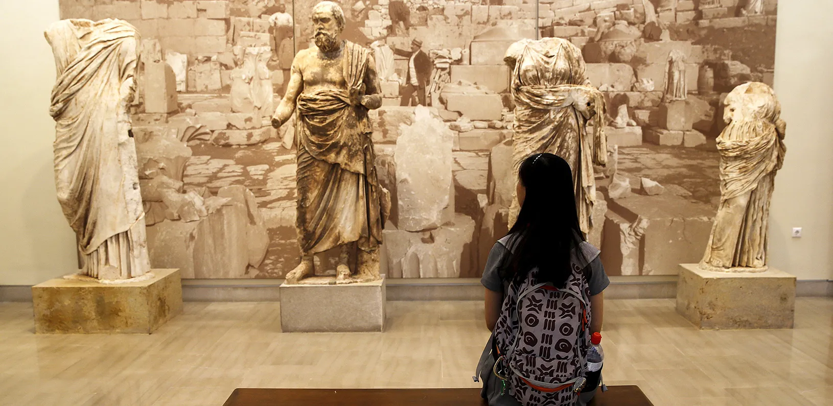 Woman sitting on a museum bench looking a sculptures