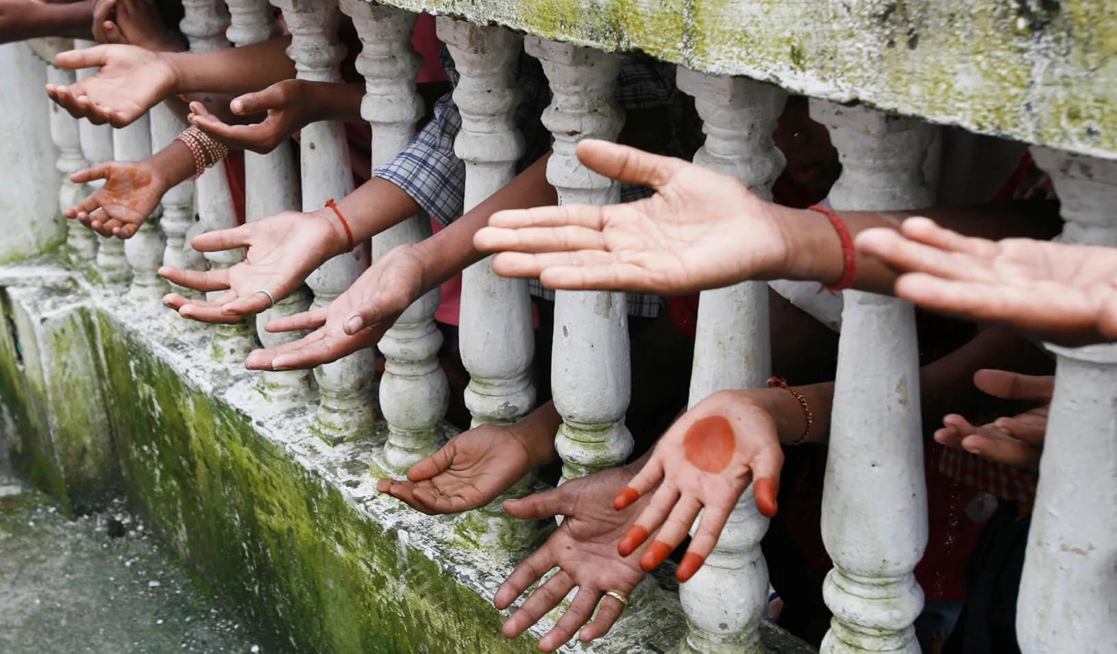 People reaching-out from behind a fence