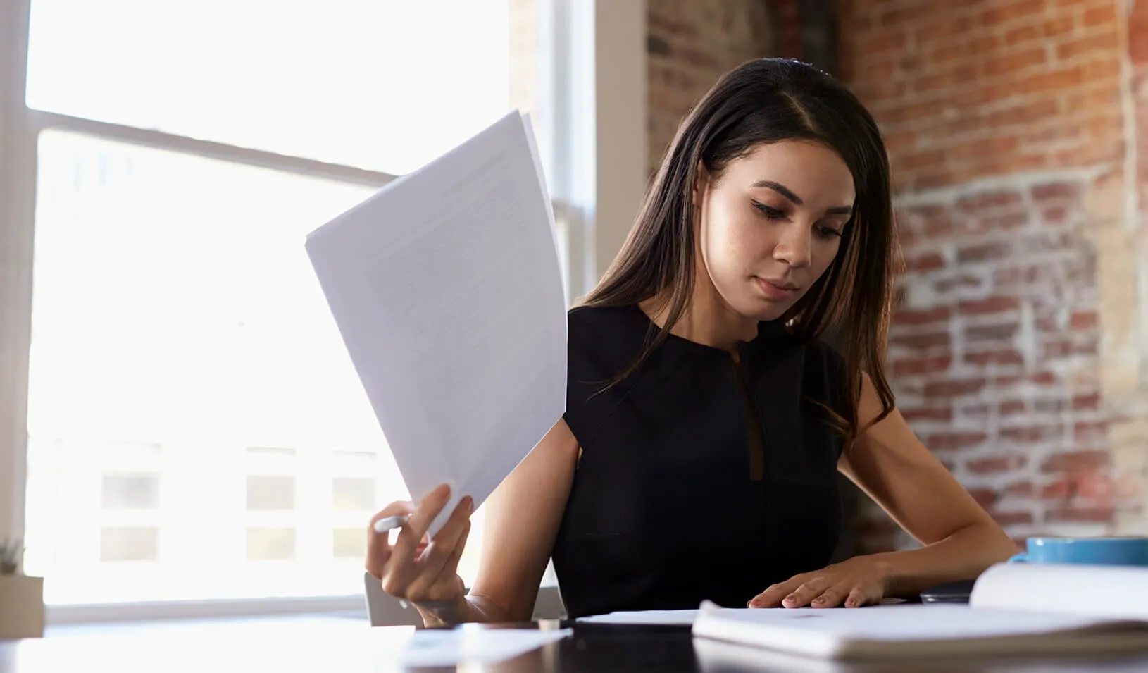 Latina woman working at her desk | iStock/monkeybusinessimages