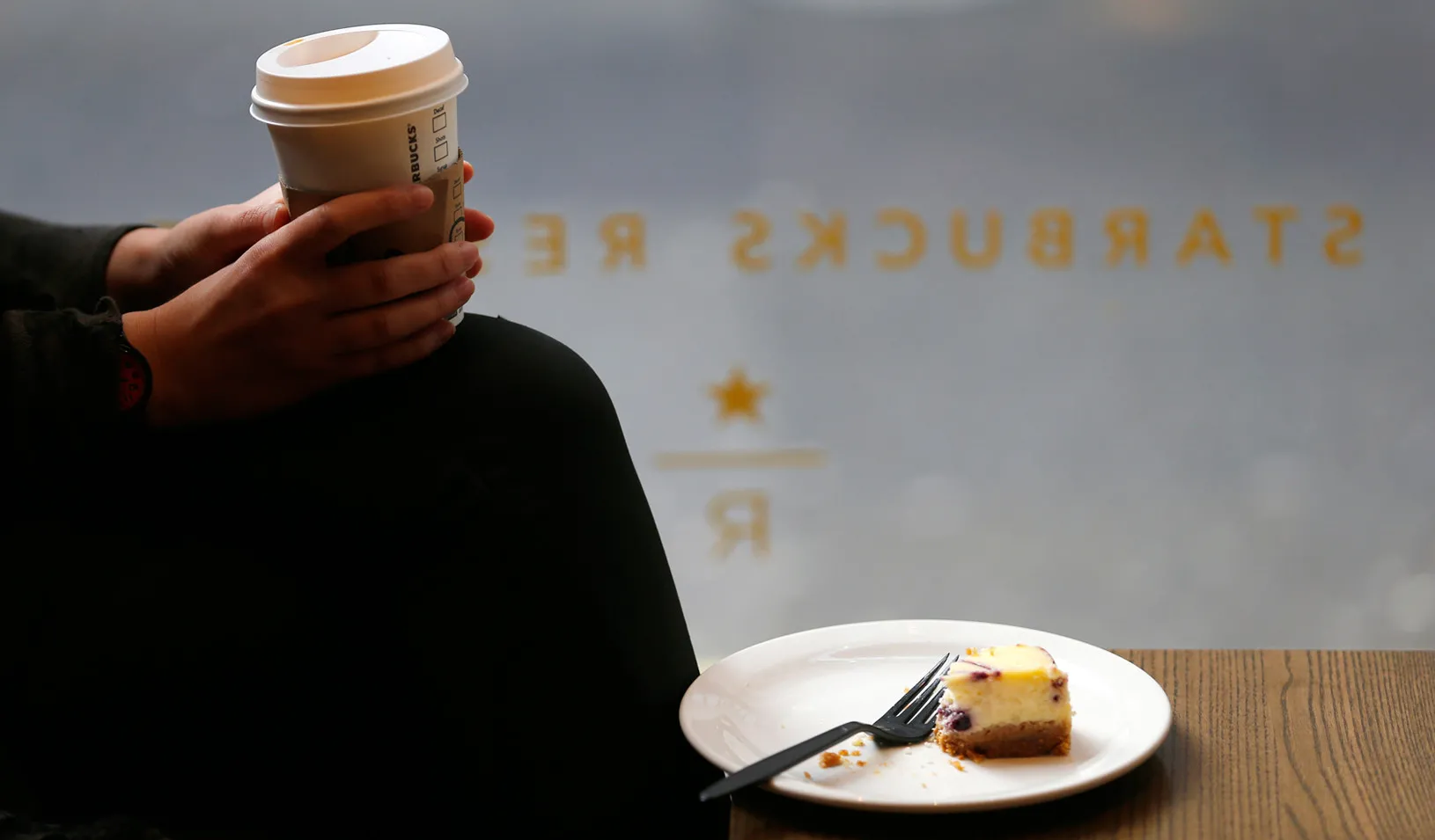A customer cradles her drink at a Starbucks in central London. (Reuters photo by Andrew Winning)