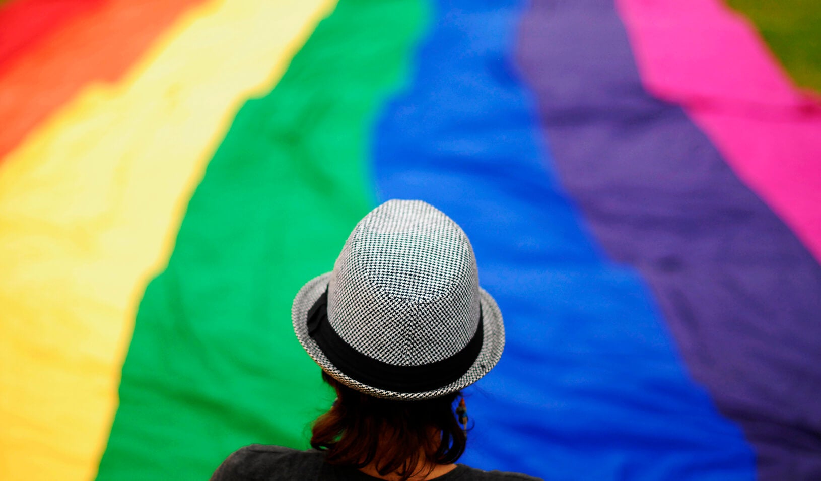 A transgender person overlooks a large rainbow banner | Reuters/Ulises Rodriguez